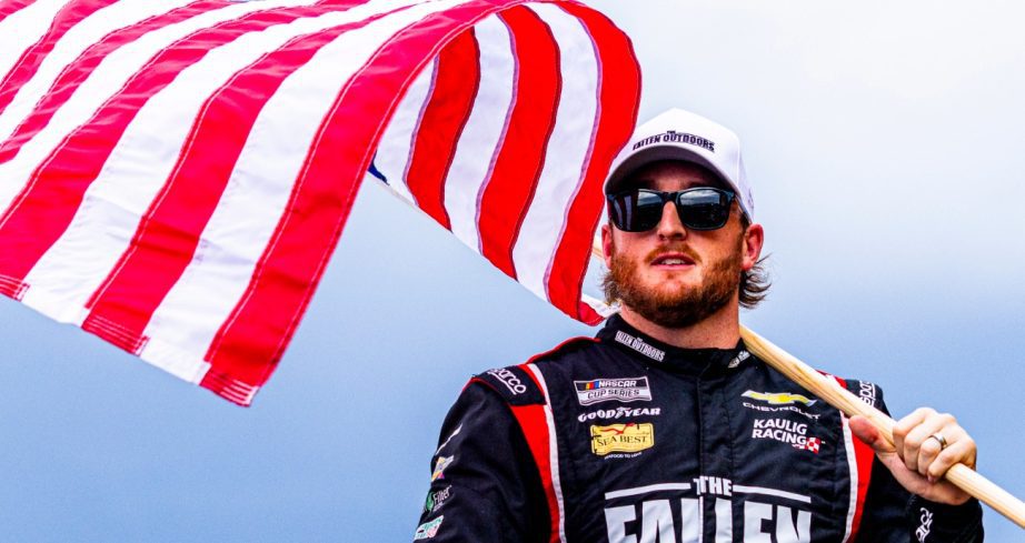 Ty Dillon holds an American flag while walking the stage.
