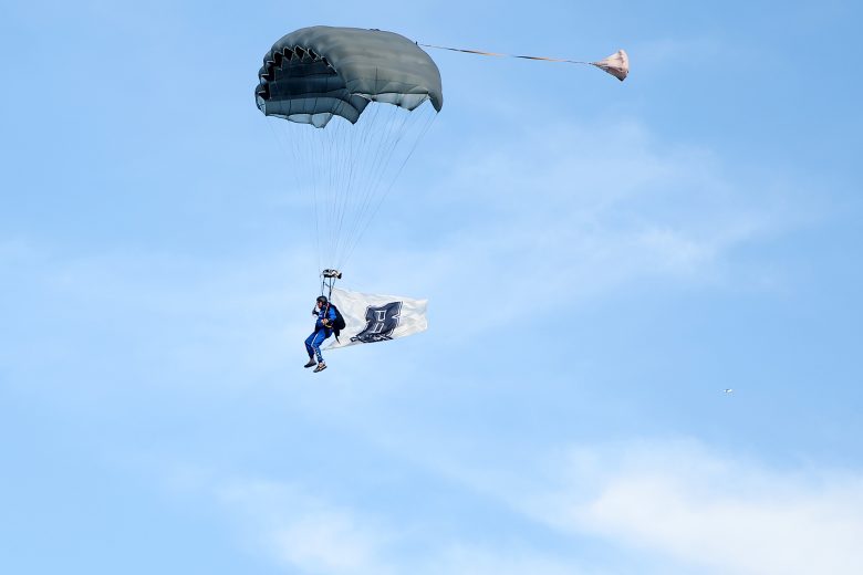 A skydiver lands during pre-race ceremonies with a Kyle Busch flag.