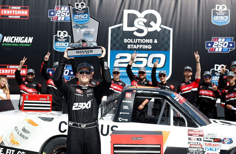 Corey Heim hoists the trophy in Victory Lane following his NASCAR Craftsman Truck Series win at Michigan International Speedway.