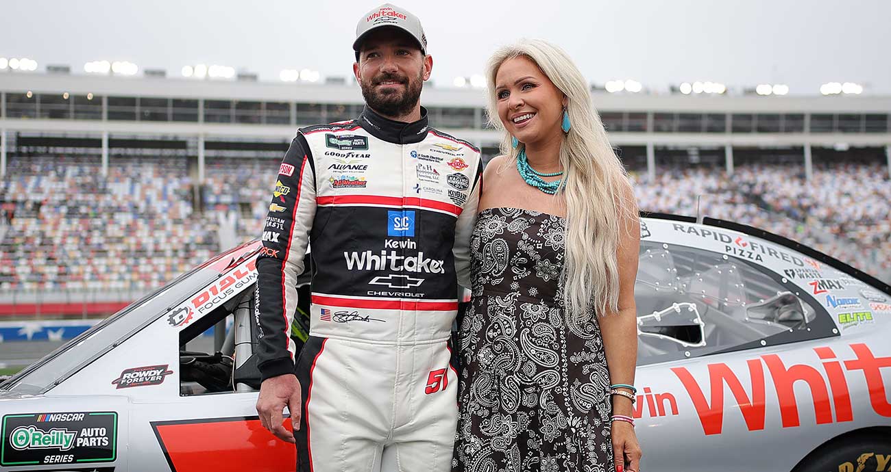 Jeremy Clements and his wife, Cortney, smile for photos on pit road at Charlotte Motor Speedway