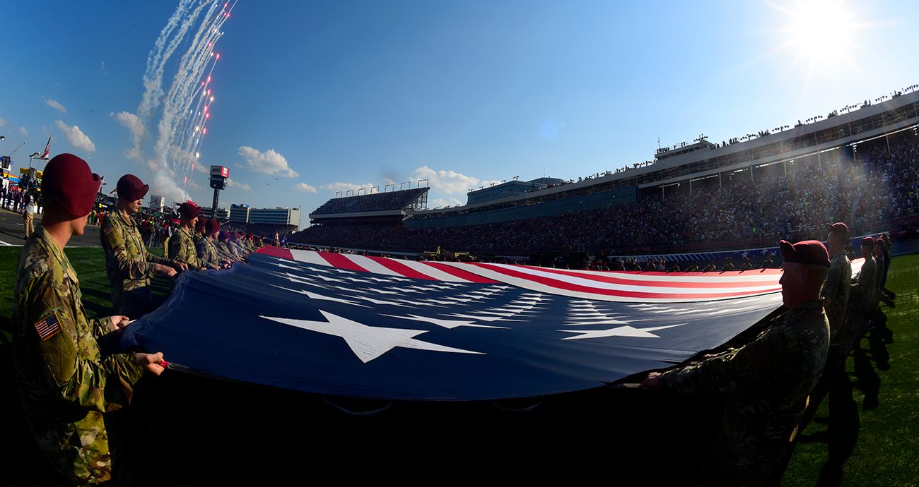 Military members display an American flag before a NASCAR race at Charlotte.