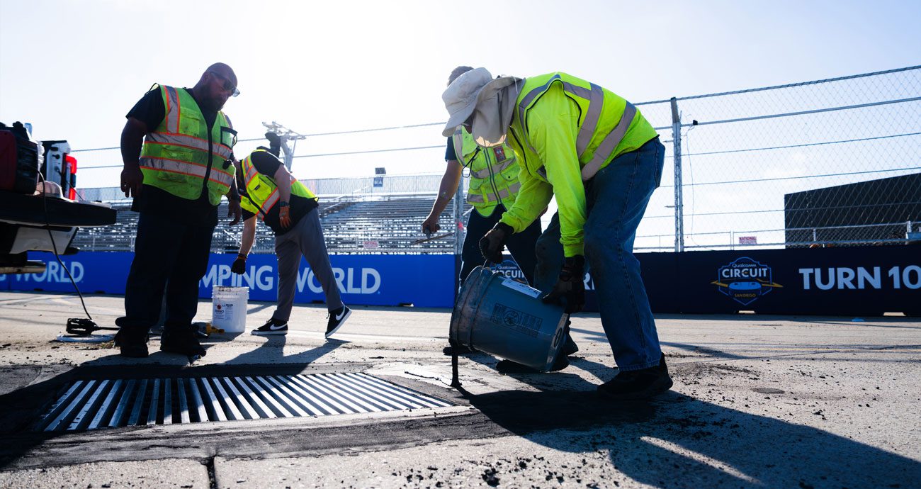 Track workers add sealer around a drain on the Naval Base Coronado NASCAR course.