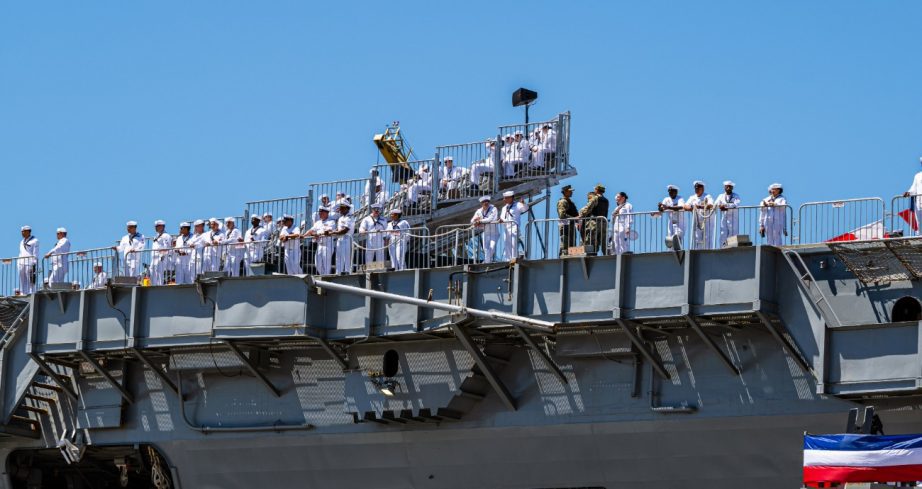 United States Navy sailors sit in the grandstands.