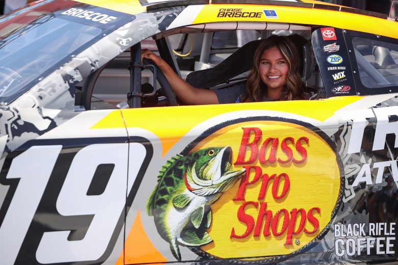 A fan sits in replica version of a Cup car.