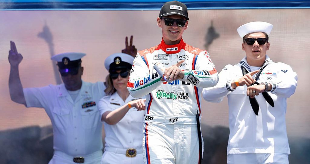 Corey Heim walks onstage with U.S. Navy service members during driver introductions at Naval Base Coronado