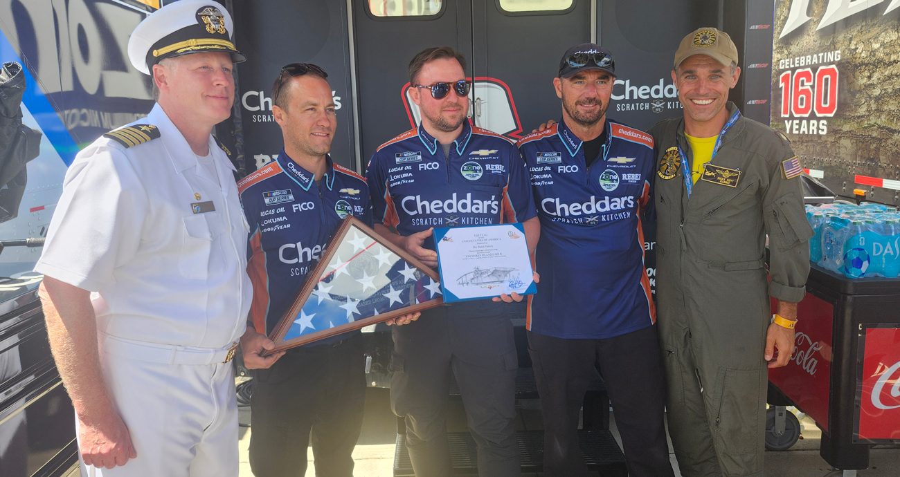 Capt. Kyle Thomas, commanding officer of the Navy Reserve Center on North Island, and Lt. Cmdr. Ricky Hoyt present Austin Hill's team with a flag that had flown over the USS Makin Island (LHD-8).