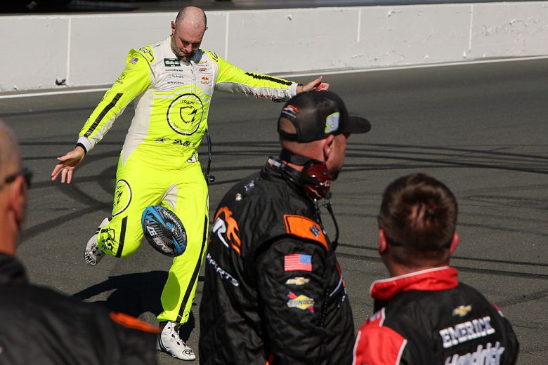 Shane van Gisbergen kicks a rugby ball at Sonoma.