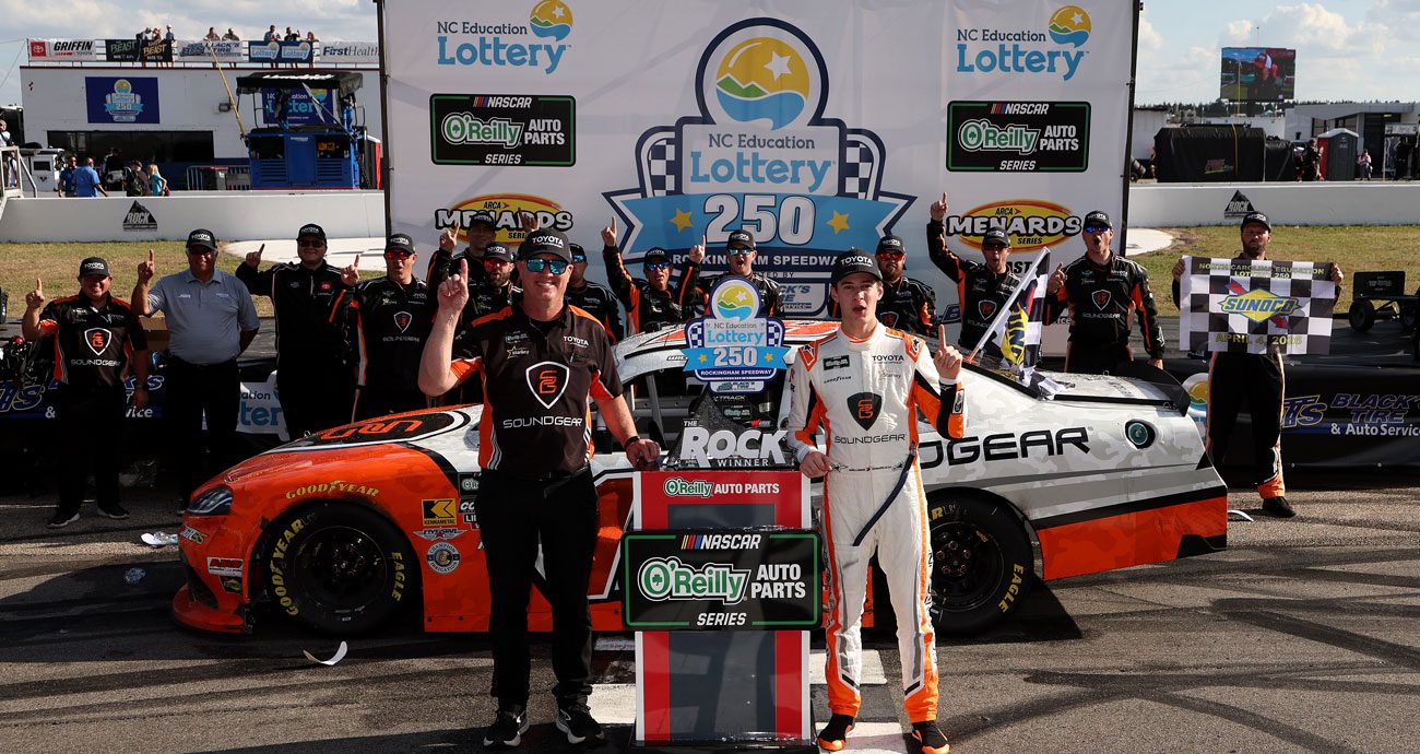William Sawalich and the No. 18 Joe Gibbs Racing team pose for a photo in Victory Lane at Rockingham Speedway.