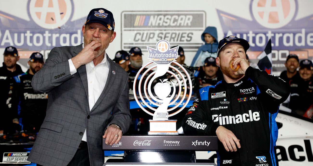 Tyler Reddick (R) eats a peach in Victory Lane at EchoPark Speedway.