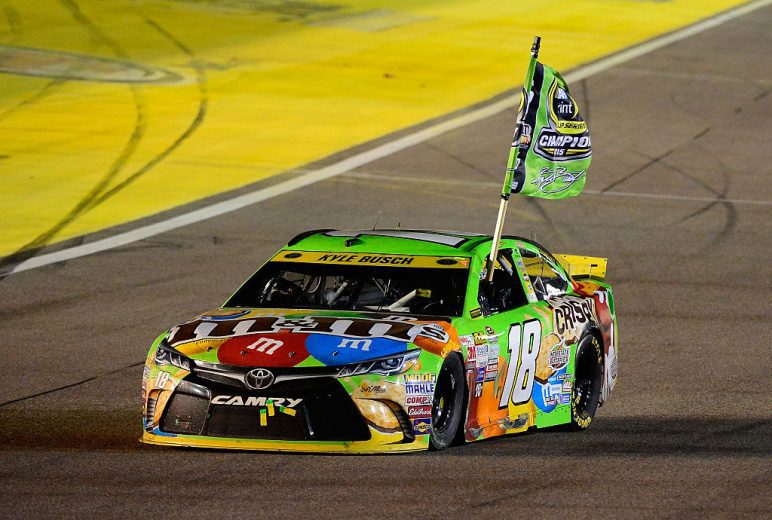 Kyle Busch drives the No. 18 Joe Gibbs Racing Toyota with a championship flag at Homestead-Miami Speedway.