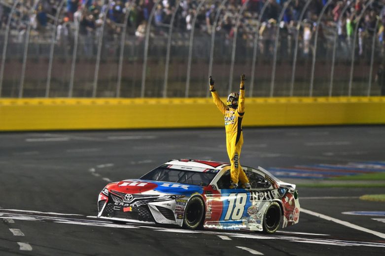 Kyle Busch stands atop his No. 18 Joe Gibbs Racing Toyota following his NASCAR Cup Series win at Charlotte Motor Speedway.