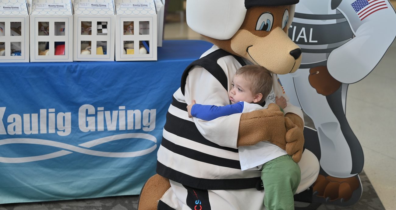 Speedy Bear hugs a child at a Speedy Bear Brigade event with Kaulig Giving and The NASCAR Foundation