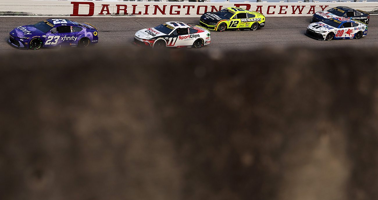 a pack of cars races at darlington
