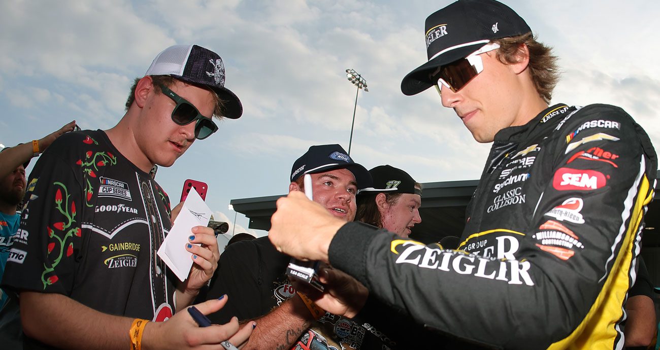 Carson Hocevar signs autographs for fans before a NASCAR Cup Series race.