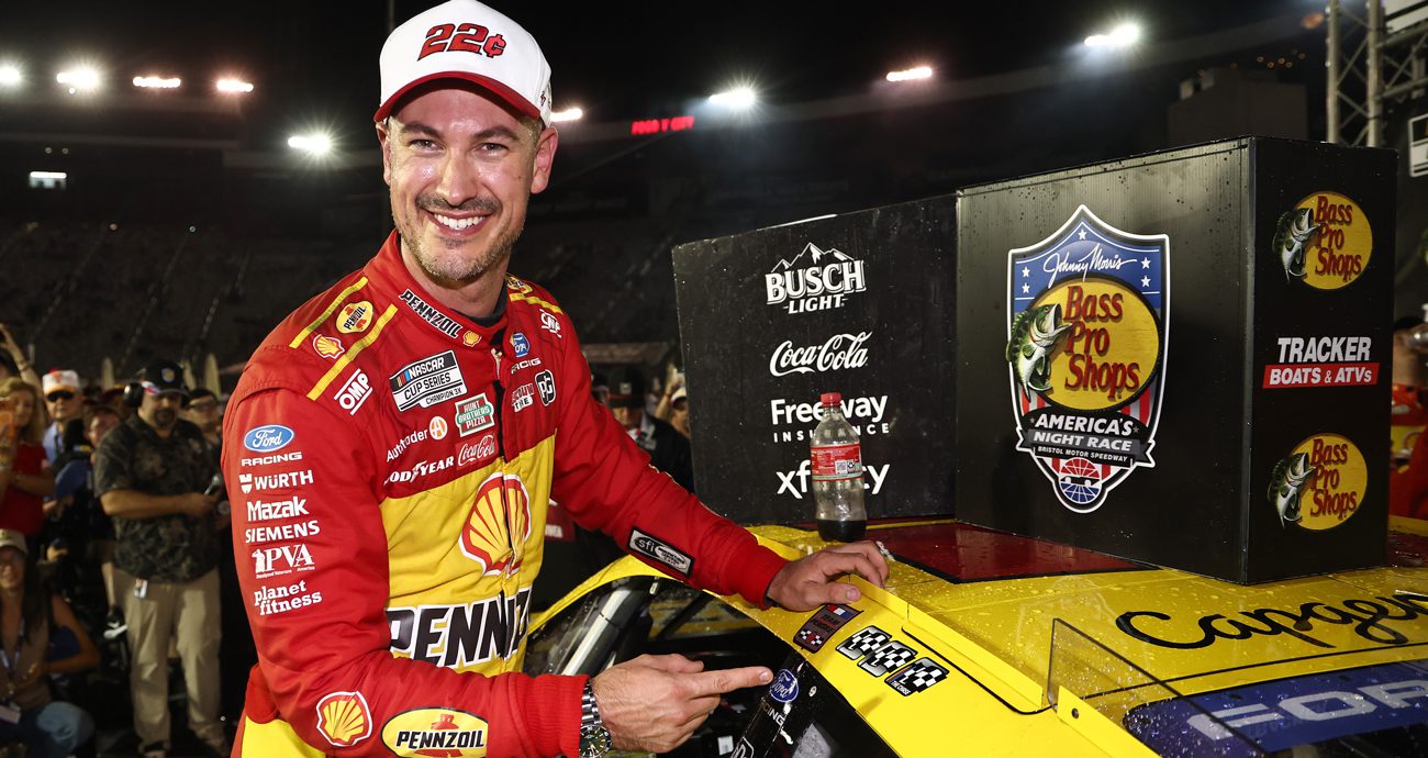 Joey Logano points at the winner sticker he put above the door on his No. 22 Ford while smiling in Victory Lane at Bristol Motor Speedway.