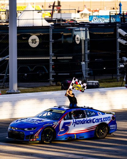 Owen Larson waves the checkered flag atop the No. 5 Hendrick Motorsports Chevrolet.